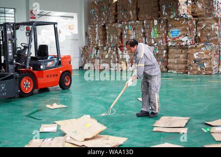 Ein chinesischer Arbeiter sortiert Recycling Abfall, der auf einer Distribution Center der erneuerbaren Energien Abfälle aus Behälter bereitgestellt werden, um das neue Müll sortieren s gerecht zu werden gesammelt Stockfoto