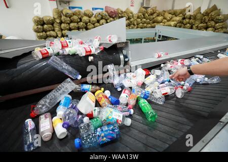 Ein chinesischer Arbeiter sortiert Recycling Abfall, der auf einer Distribution Center der erneuerbaren Energien Abfälle aus Behälter bereitgestellt werden, um das neue Müll sortieren s gerecht zu werden gesammelt Stockfoto