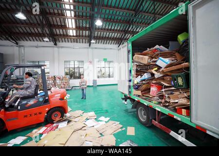 Ein chinesischer Arbeiter sortiert Recycling Abfall, der auf einer Distribution Center der erneuerbaren Energien Abfälle aus Behälter bereitgestellt werden, um das neue Müll sortieren s gerecht zu werden gesammelt Stockfoto