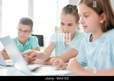 Kluger junge pointing at laptop Display, solange etwas zu zeigen Mädchen Stockfoto