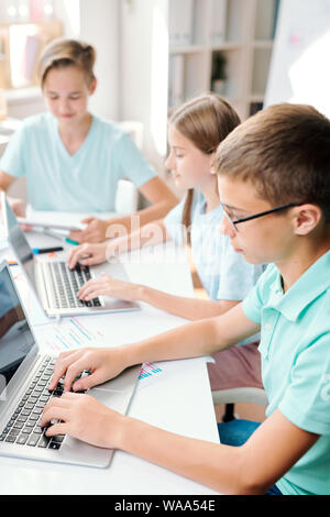 Zwei Jungen und Mädchen sitzen vor der Laptops, die bei der abschließenden Prüfung Test Stockfoto