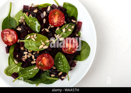Gesunde vegetarische Nahrung. Salat mit roter Bete, Spinat, Tomaten und Samen. Stockfoto