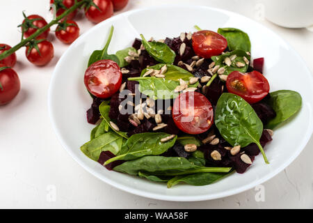 Gesunde vegetarische Nahrung. Salat mit roter Bete, Spinat, Tomaten und Samen. Stockfoto
