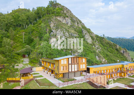 Luftaufnahme von Holzhäuser und Hotels im Altai Gebirge zwischen den Felsen und grünen Bäumen für Entspannung und Unterkunft während touristische Ausflüge ein Stockfoto