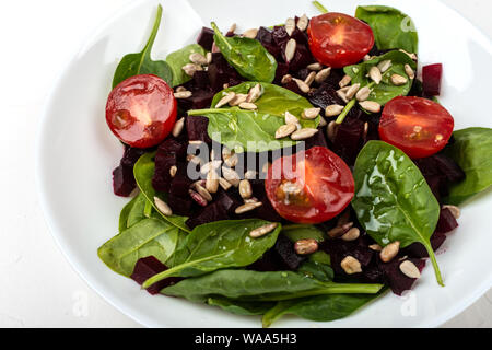 Gesunde vegetarische Nahrung. Salat mit roter Bete, Spinat, Tomaten und Samen. Stockfoto