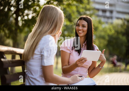 Zwei Kollegen sitzen im Park und im Gespräch in der Pause. Stockfoto