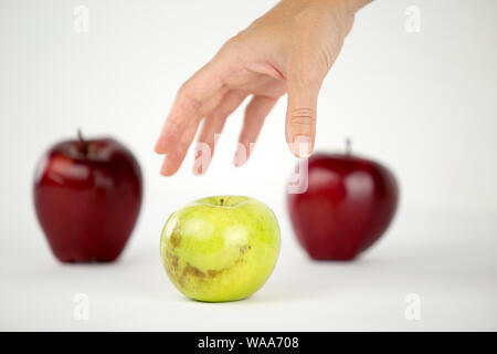 Konzept der Vielfalt: die Hand einer Frau ist über die einzige Green Apple unter den anderen roten zu ergreifen Stockfoto