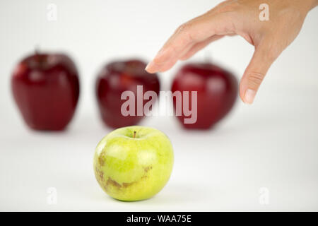 Konzept der Vielfalt: die Hand einer Frau ist über die einzige Green Apple unter den anderen roten zu ergreifen Stockfoto