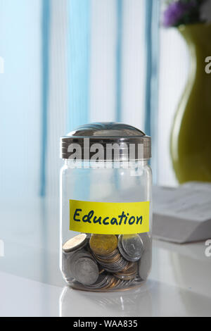 Glas mit indischen Münzen mit "Bildung" darauf geschrieben Stockfoto