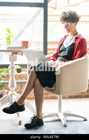 Junge elegante Geschäftsfrau, Computer arbeiten im Sessel sitzt Stockfoto