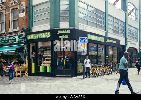 London/Großbritannien - 16. Juli 2019: Menschen zu Fuß vorbei an der jamaikanische Küche Restaurant gesunde Esser in Brixton; das ist ein Viertel von South London, mit Stockfoto