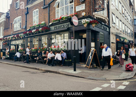 London, UK/16 Juli 2019: Menschen sitzen an den Tischen außerhalb des Prinzen von Wales Pub auf dem Longmoore Street in Pimlico, London, UK. Pubs sind die b Stockfoto