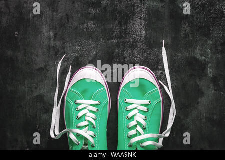 Blau - blaugrün - Grün - türkis Sneaker mit Ungebundener Schnürsenkel auf einem dunklen konkreten Hintergrund. Kopieren Sie Platz. Ansicht von oben Stockfoto