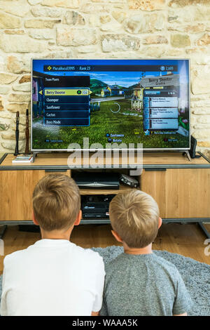 Zwei Jungen spielen ein Spiel auf einem großen Bildschirm. Stockfoto