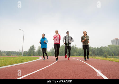 Vier junge männliche und weibliche Athleten in Sportkleidung läuft Marathon Stockfoto