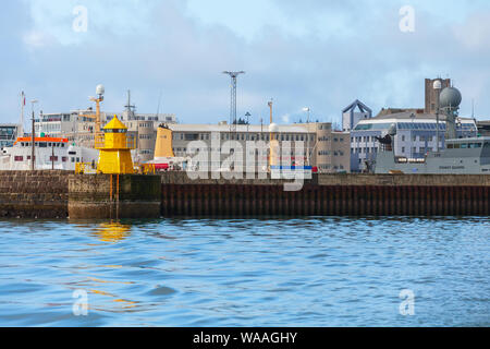 Reykjavik, Island - 4. April 2017: Gelb Lighthouse Tower auf Stein wellenbrecher am Eingang nach Reykjavik cargo Port montiert Stockfoto