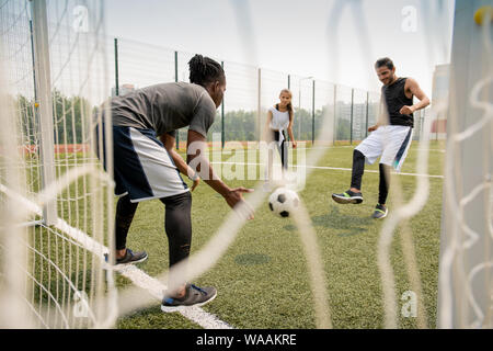Junge afrikanische Fußball-Spieler den Ball zu fangen, während sein Rivale es treten Stockfoto