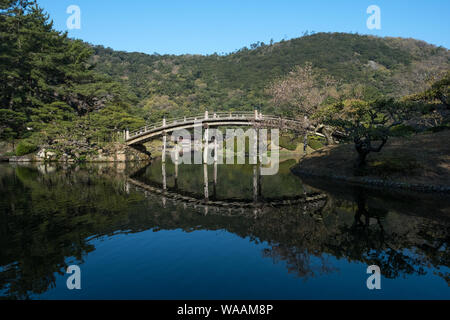 Crescent Mond-Brücke und ein blauer Himmel im Ritsurin Garden in Shikoku, Japan Stockfoto