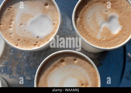 Eine Nahaufnahme Blick von oben auf die drei Tassen Cappuccino Kaffee auf einem silbernen Tablett Stockfoto