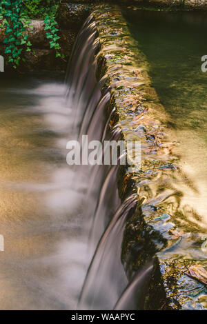 Kleinen Berg Wasserfall auf den Felsen mit Moos im Wald bedeckt Stockfoto