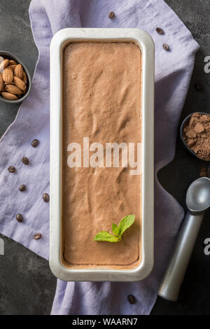 Banane Schokolade hausgemachtes Eis in metallischen Behälter auf schwarzem Hintergrund. Blick von oben. Sauber, Essen. Ohne Zucker. Stockfoto