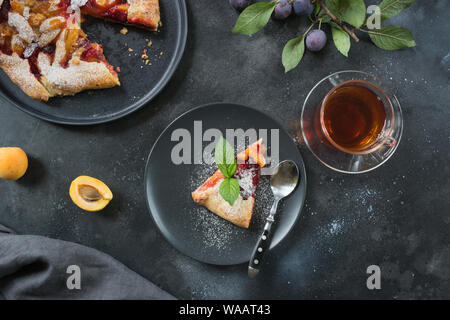 Lecker fallen pie Galette mit frischen Pflaumen und Aprikosen auf Schwarz. Blick von oben. Horizontale erschossen. Stockfoto