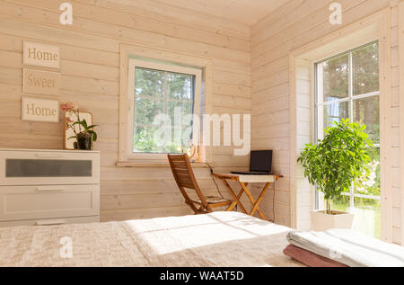 Gemütliche helle Zimmer in einem Holzhaus im skandinavischen Stil mit dekorativen Blumen in Töpfe Stockfoto