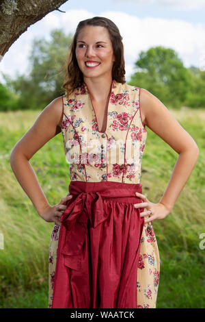 Porträt der jungen Frau im Dirndl durch Baum stehend Stockfoto