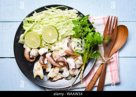 Gegrillter Tintenfisch Salat mit Kalk Kräuter und Gewürze auf Esstisch/Tentakeln Krake warme Vorspeise essen heiß und würzig Meeresfrüchte serviert, gekocht auf der Platte Stockfoto