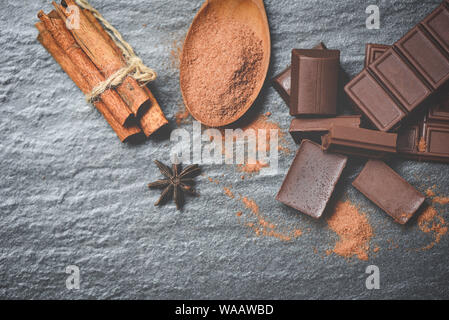 Schokolade und Gewürzen auf dunklem Hintergrund / Pulver Schokolade auf Löffel und Stücke candy süße Nachspeise für Snack, selektiven Fokus Stockfoto