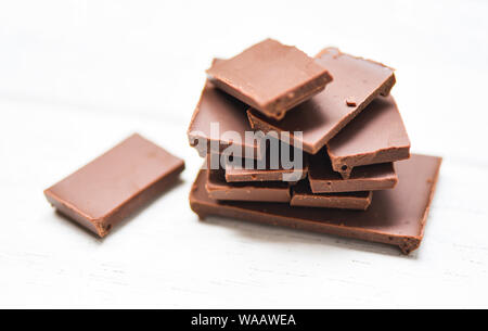 Schokolade auf dem weißen Holz Hintergrund/close up Schokolade Stück candy süße Nachspeise und Snack gestapelt, selektiver Fokus Stockfoto