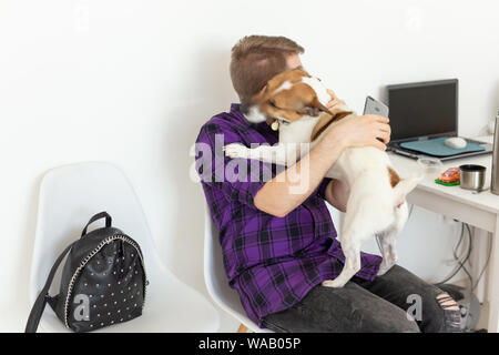 Menschen, Haustiere und Tiere Konzept - junge Mann umarmt Jack Russell Terrier und versuchen zu arbeiten. Stockfoto