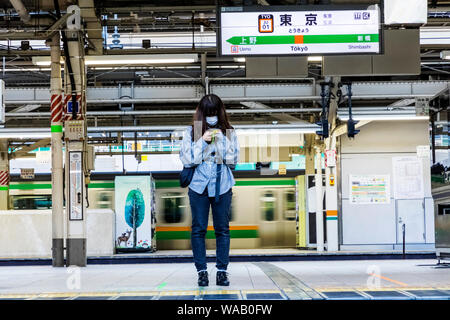 Japan, Honshu, Tokio, Tokyo Station, Yamanote Linie Plattform, junge Frau mit Maske Warten auf Zug, 30076250 Stockfoto