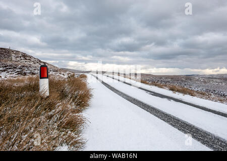 Deutliche Spuren an einem verschneiten Straße in ländlicher Umgebung mit einem stürmischen Himmel und Raum für Kopie Stockfoto