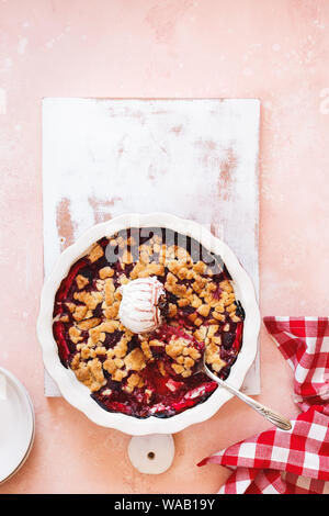 Berry in Auflaufform mit Vanilleeis und Löffel bröckeln. Ansicht von oben, leeren Raum Stockfoto