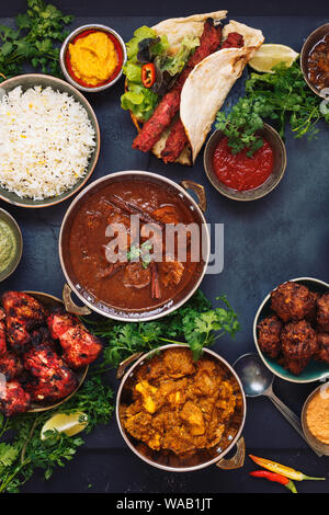 Verschiedene indische Gerichte mit Rogan Josh, Chicken Tikka Masala, Tandoori Chicken Wings und Kebabs, mit Reis und Naan Brot, Ansicht von oben Stockfoto