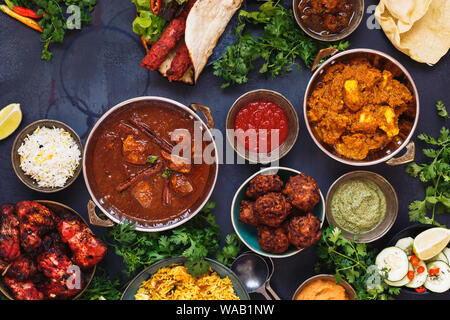Geschmack von Indien. Eine Auswahl an indischen Speisen mit verschiedenen Schüsseln mit Essen mit Chicken Tikka Masala, Rogan Josh, Kebabs, Tandoori Chicken Wings, Pas Stockfoto