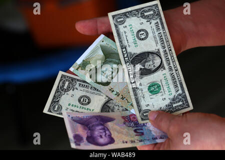 Dollar vs Yuan. Dollar und Yuan in den Händen Stockfoto