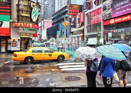 NEW YORK, USA - 10. JUNI 2013: die Menschen besuchen regnerischen Times Square in New York. Den Platz an der Kreuzung von Broadway und 7. Avenue hat einige 39 Millionen visi Stockfoto