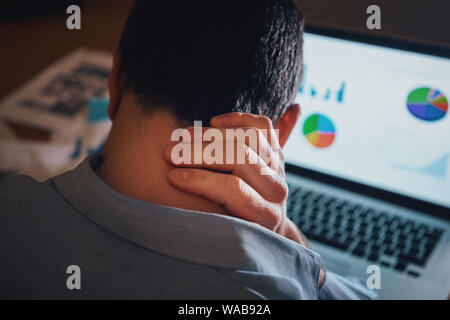 Männliche freelancer Arbeiten am Laptop leiden unter Nackenschmerzen Stockfoto