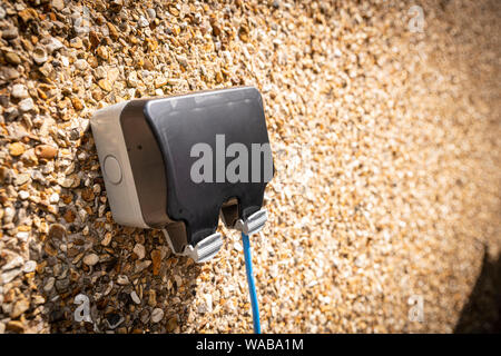 Inländische im Freien elektrische Steckdose Wasserdichte Box mit blauem Kabel läuft. Stockfoto