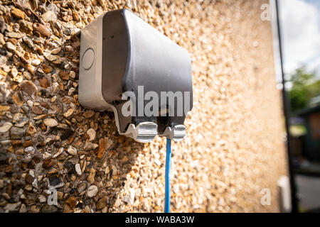 Inländische im Freien elektrische Steckdose Wasserdichte Box mit blauem Kabel läuft. Stockfoto