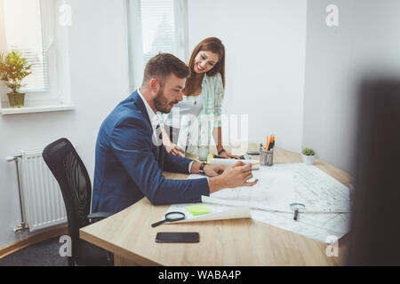 Zwei junge Architekten Kommunikation während der Überprüfung Blaupausen für ein neues Projekt im Büro. Stockfoto