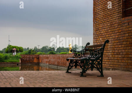 Ruhestuhl in Lumbini, Nepal, an eine Ziegelwand angehängt Stockfoto