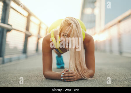 Young Sport Frau tun plank Übung auf der Brücke während outdoor Cross Training durch den Fluss fokussiert. Stockfoto