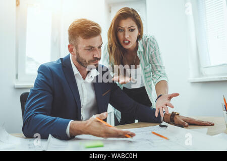 Zwei junge besorgt Architekten Analyse Problem auf die Blaupausen für ein neues Projekt im Büro. Stockfoto