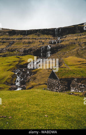 Altes Haus in der Nähe eines Wasserfalls in Saksun, Färöer Inseln Stockfoto