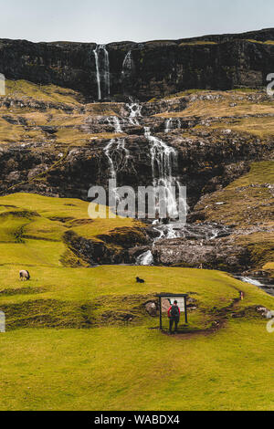 Unbekannter Tourist in der Nähe eines Wasserfalls in Saksun, Färöer Inseln Stockfoto