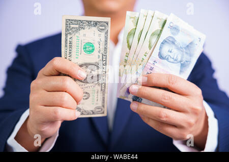 Geld in China und den USA halten an Hand der Mann trägt einen blauen Anzug CNY, USD zu Zahlen, die exchange Geld Volksrepublik China (VRC), Amerika auf Weiß b Stockfoto