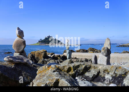 Balancing Steine am Strand von Marazion, Cornwall mit St. Michael's Mount im Hintergrund - Johannes Gollop Stockfoto